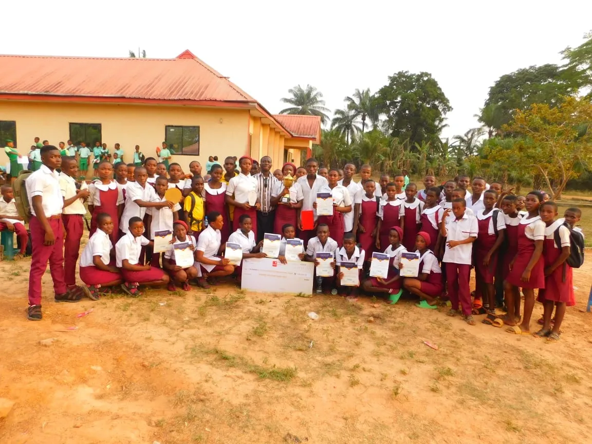 A large group of students in uniform holding certificates outside the event hall