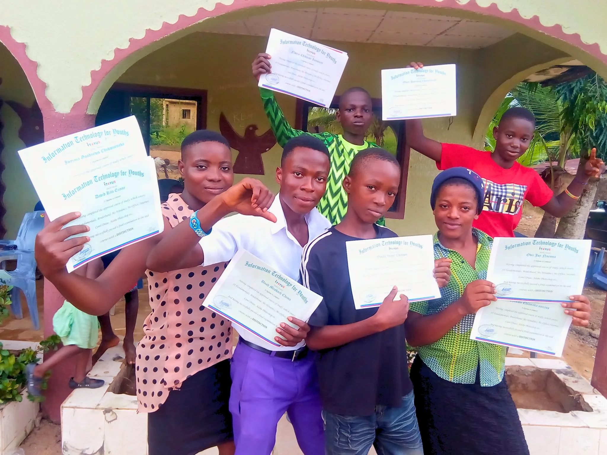 Smiling IT4YUS scholars holding up their certificates outside the centre in Oshiri