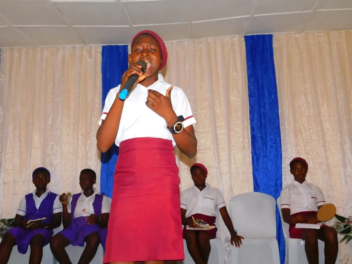 A student in a maroon skirt speaks passionately into a microphone at the IT Debate